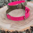 Handmade two-colour BioThane dog collar in hot pink and sage green, displayed on a wooden disc with desert plants.