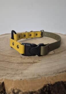The Quick-Snap Bungee Collar, featuring yellow and olive green colours with a black quick-snap buckle, rests on a round wooden surface displaying visible tree rings.