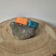 Centre O-Ring Collar in orange and teal Biothane, displayed on a stone and wooden surface, showing the dual-strap design.