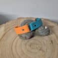 Biothane Centre O-Ring Collar in vibrant orange and turquoise, displayed on natural wood and stone, showcasing the independent strap design.