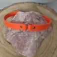 Bright orange Biothane centre O-ring collar displayed on a textured stone, showcasing the rollover safety design for active gundogs.