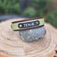 Handmade BioThane dog collar in sage green and burgundy with navy nameplate, displayed on stone.