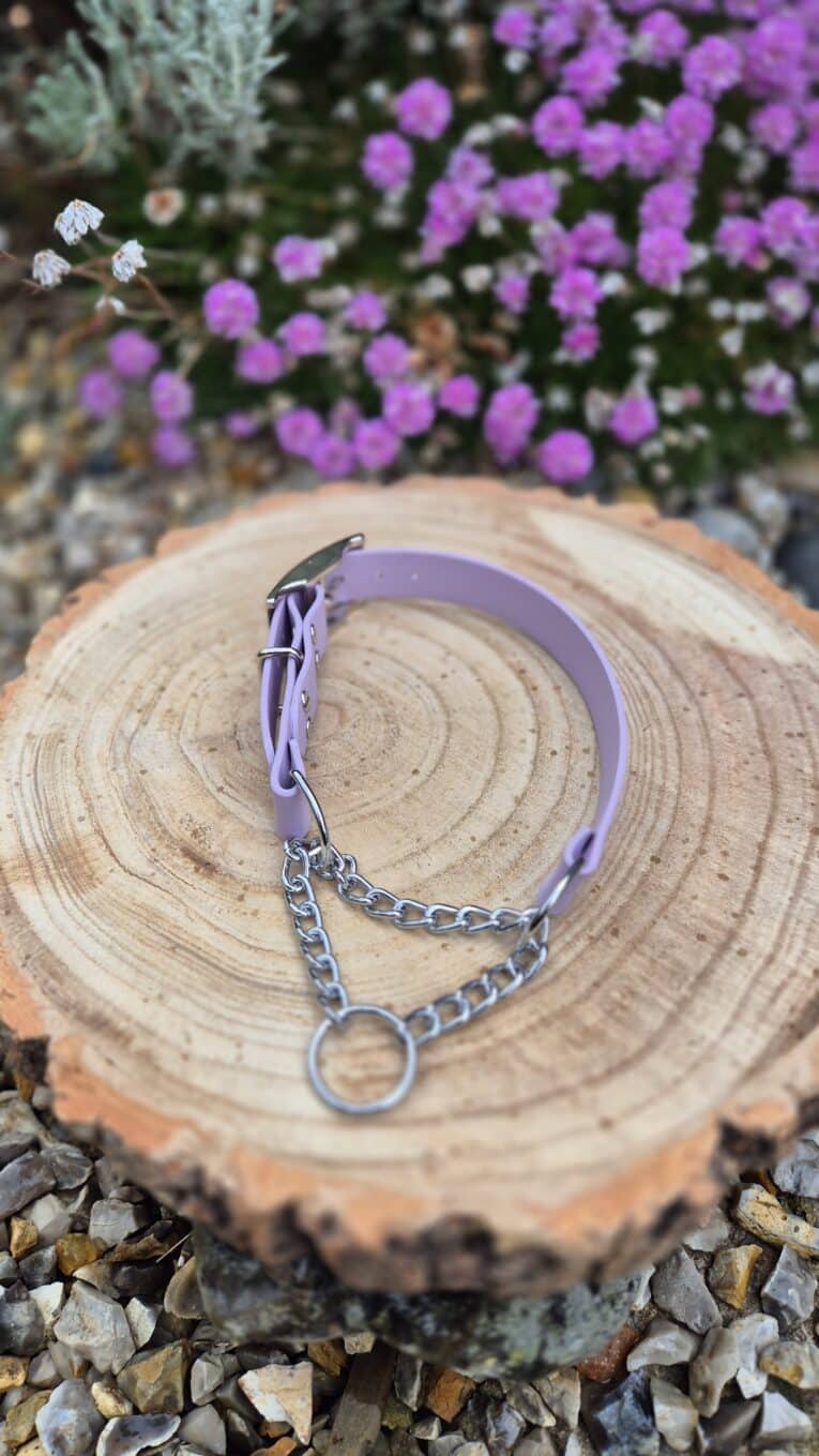 Lavender handmade BioThane dog collar with chain martingale displayed on natural wood, surrounded by purple flowers.