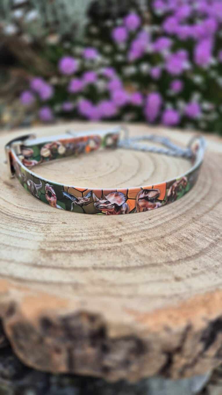 Handmade BioThane dog collar with vibrant comic-print design, displayed on natural wood with purple flowers in background.