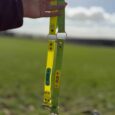 Hand holding a yellow and green Centre O-Ring Collar Gundog Collar, displaying the independent strap movement design outdoors.