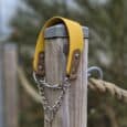 Bright yellow Biothane martingale half-check dog collar with brown BioThane handle and stainless steel chain, mounted on wooden post.