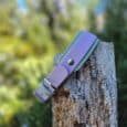 Purple and teal double-layered Hound Collar displayed on a weathered wooden post, showcasing the practical layered design and stainless steel hardware detail.
