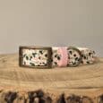 Printed customisable dog collar with floral pattern, brass fittings, and pink keeper on wooden surface.