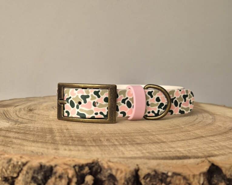 Printed customisable dog collar with floral pattern, brass fittings, and pink keeper on wooden surface.