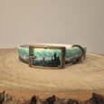 Handmade BioThane dog collar featuring a mountain forest landscape design with teal and charcoal tones, displayed on natural wood.
