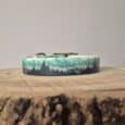 Handmade BioThane dog collar with layered mountain and forest design in green and charcoal, displayed on wooden surface.