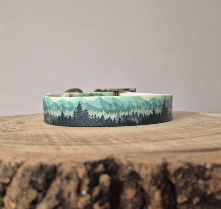 Handmade BioThane dog collar with layered mountain and forest design in green and charcoal, displayed on wooden surface.