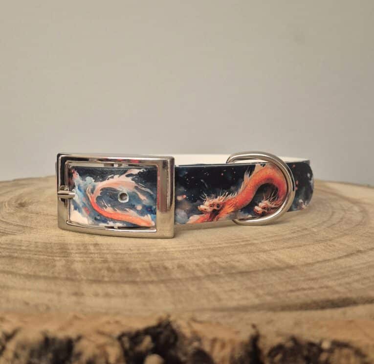 Handmade BioThane dog collar featuring vibrant red dragon artwork on dark fabric, displayed on natural wood with matching D-ring and metal buckle.