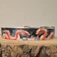 Handmade BioThane dog collar featuring vibrant red dragons on dark background, displayed on wooden surface.