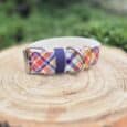 Colourful argyle-patterned quick-snap customisable dog collar in extra wide full print design, displayed on natural wood with metal hardware and navy blue side release buckle.