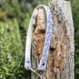 Printed Slip and Clip collar in blue floral design draped over weathered wood post, showing nickel hardware and versatile O-ring attachment system outdoors.