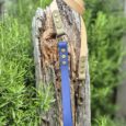 Handmade BioThane dog lead in blue and cream with brass fittings, displayed on weathered wood outdoors.