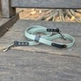 Deep forest multiway lead with brass hardware and black BioThane handles, coiled on weathered wood.