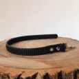 Black BioThane grip tag collar with metal hardware on wooden surface.