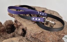 Midnight amethyst and black handmade BioThane dog collars and lead displayed on textured stone.