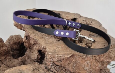 Midnight amethyst and black handmade BioThane dog collars and lead displayed on textured stone.