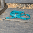 Turquoise multiway lead with brass fittings and D-ring, displayed on rustic wooden fence.