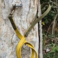 Saffron yellow handmade BioThane dog lead with brass hardware, attached to weathered wooden post.