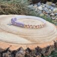Handmade BioThane tag collar in lavender with floral printed design, displayed on wooden disc.