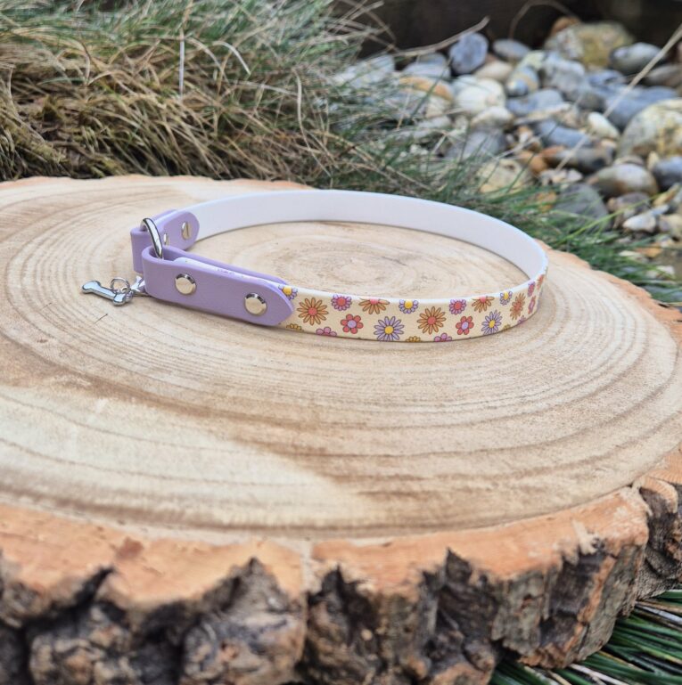 Handmade BioThane tag collar in lavender with floral printed design, displayed on wooden disc.