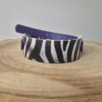 Zebra-striped handmade BioThane dog collar with navy blue strap and white hardware on wooden surface.