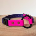 Handmade BioThane dog collar in vibrant pink and navy with black hardware, displayed on natural wood.