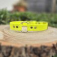 Bright yellow BioThane gundog collar with metal ring and studs, displayed on weathered wood outdoors.