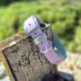 Lavender BioThane hound collar with blue hardware, displayed on weathered wood outdoors.