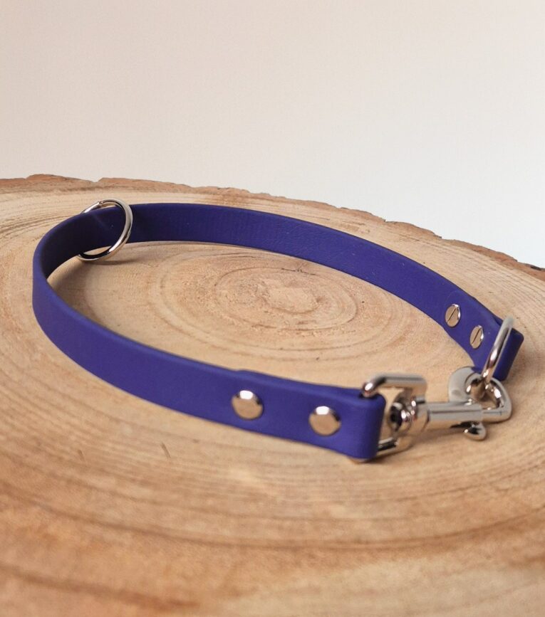 Handmade BioThane slip and clip dog collar in royal blue with silver hardware on natural wood.