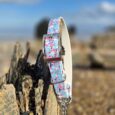 Blue floral printed BioThane dog collar with silver hardware, displayed on weathered wood outdoors.