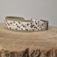 Handmade BioThane hound collar with pink, black and stone camouflage pattern and metal buckle on wooden surface.