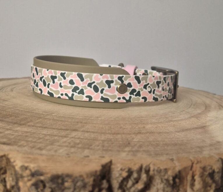Handmade BioThane hound collar with pink, black and stone camouflage pattern and metal buckle on wooden surface.