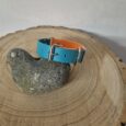 Bright blue and orange centre ring dog collar with silver hardware, displayed on natural wood with stone.