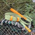 Sage green handmade BioThane dog collar and lead set with bright orange accents and brass hardware, displayed on weathered rope.