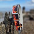 Flames collar with chrome hardware draped over weathered wood, coastal setting with blue sky behind