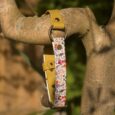 Yellow BioThane gundog collar with floral printed centre section and metal fittings, displayed on wooden branch.
