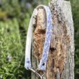 Blue floral slip collar with silver hardware draped over weathered wooden post outdoors.