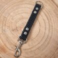 Black BioThane grab tag with metal hardware and stud detailing on wooden surface.