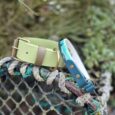 Lime green handmade BioThane dog collar with teal handle, displayed on mossy branch