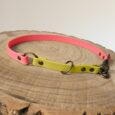 Bright pink and yellow handmade BioThane dog collar half slip with metal fittings on wooden surface.