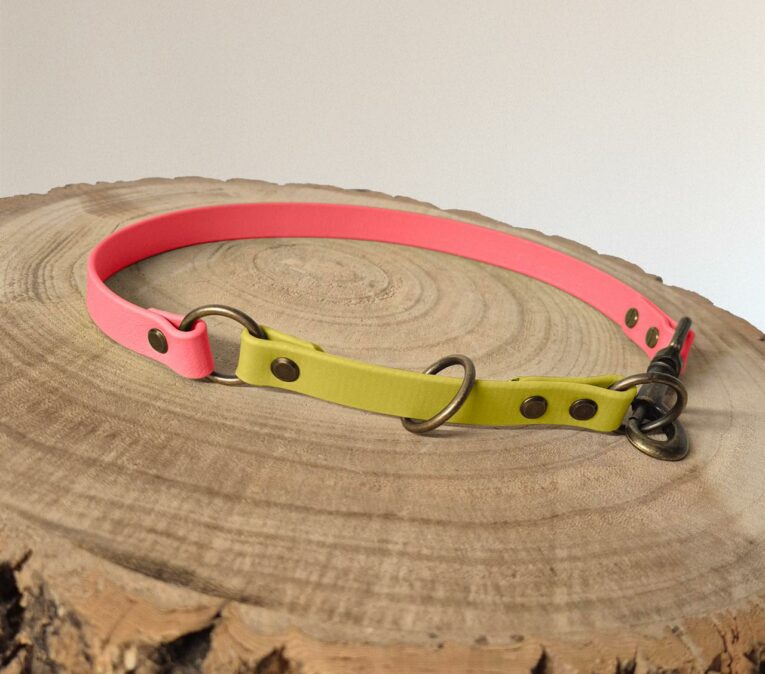 Bright pink and yellow handmade BioThane dog collar half slip with metal fittings on wooden surface.