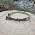 Handmade BioThane half slip collar in sage green and brown with brass hardware, displayed on natural wood.