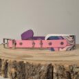 Pink and purple handmade BioThane dog collars with metal hardware displayed on wooden surface.