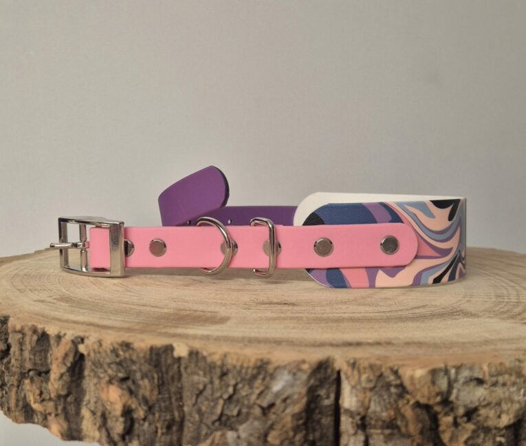 Pink and purple handmade BioThane dog collars with metal hardware displayed on wooden surface.