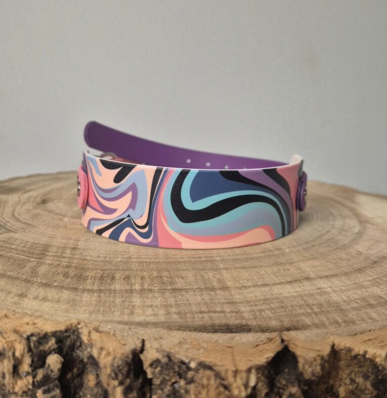 Vibrant handmade BioThane dog collar with swirling pink, purple, and blue abstract pattern, displayed on natural wood.